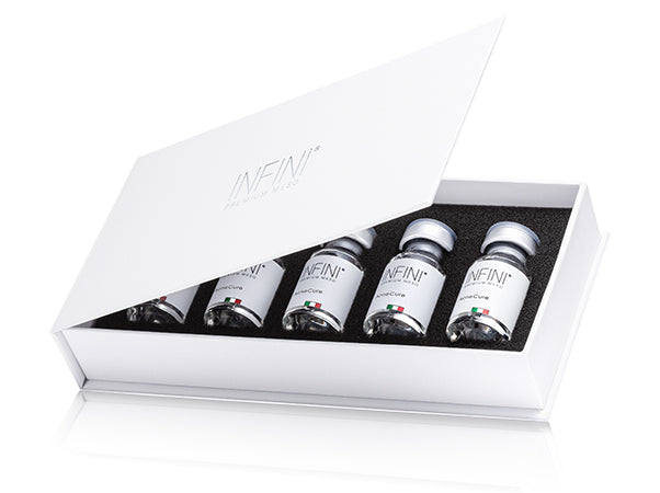 Set of INFINI skincare bottles in a white box on a white background
